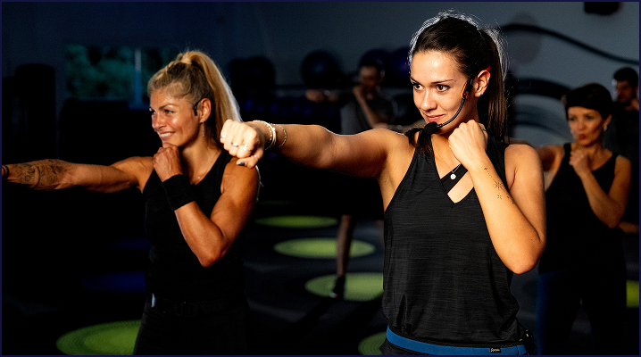 Deux femmes participants à un cours de boxe collectif animé par une coach à olympe fitness
